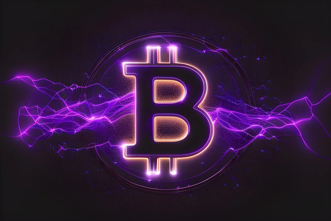 Close-up de uma moeda física dourada de Bitcoin sobre um teclado de computador iluminado com luzes neon azuis e roxas, refletindo gráficos financeiros digitais.