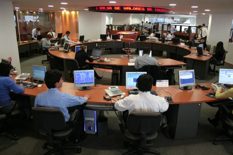 Gráfico financeiro digital exibindo uma linha de tendência em queda acentuada, com o nome 'COLCAP' e o número '-1,06%' em destaque. Moedas colombianas e um mapa estilizado da Colômbia ao fundo, simbolizando o mercado financeiro do país em declínio.
