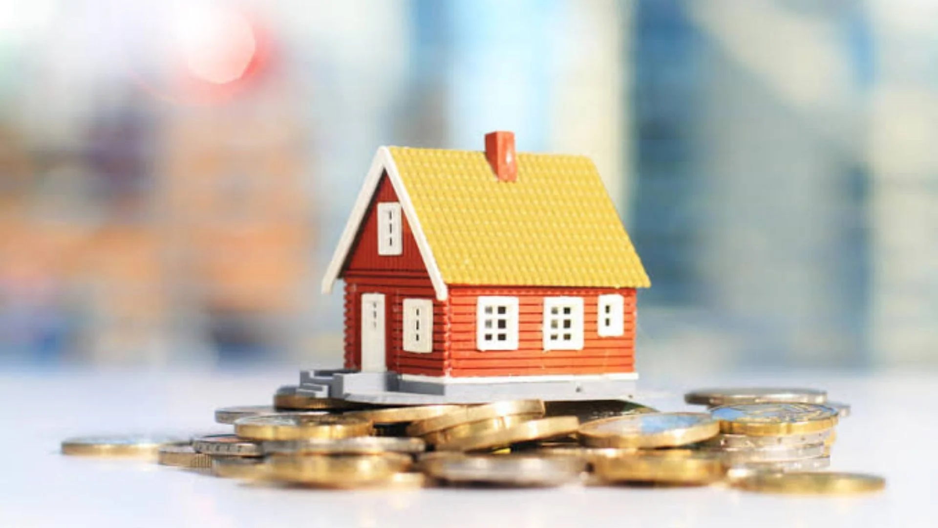Uma família sorridente, composta por um casal e dois filhos pequenos, está em pé na frente de uma casa moderna e luminosa, segurando chaves, simbolizando a conquista do lar próprio através do financiamento imobiliário. O céu está azul e ensolarado.