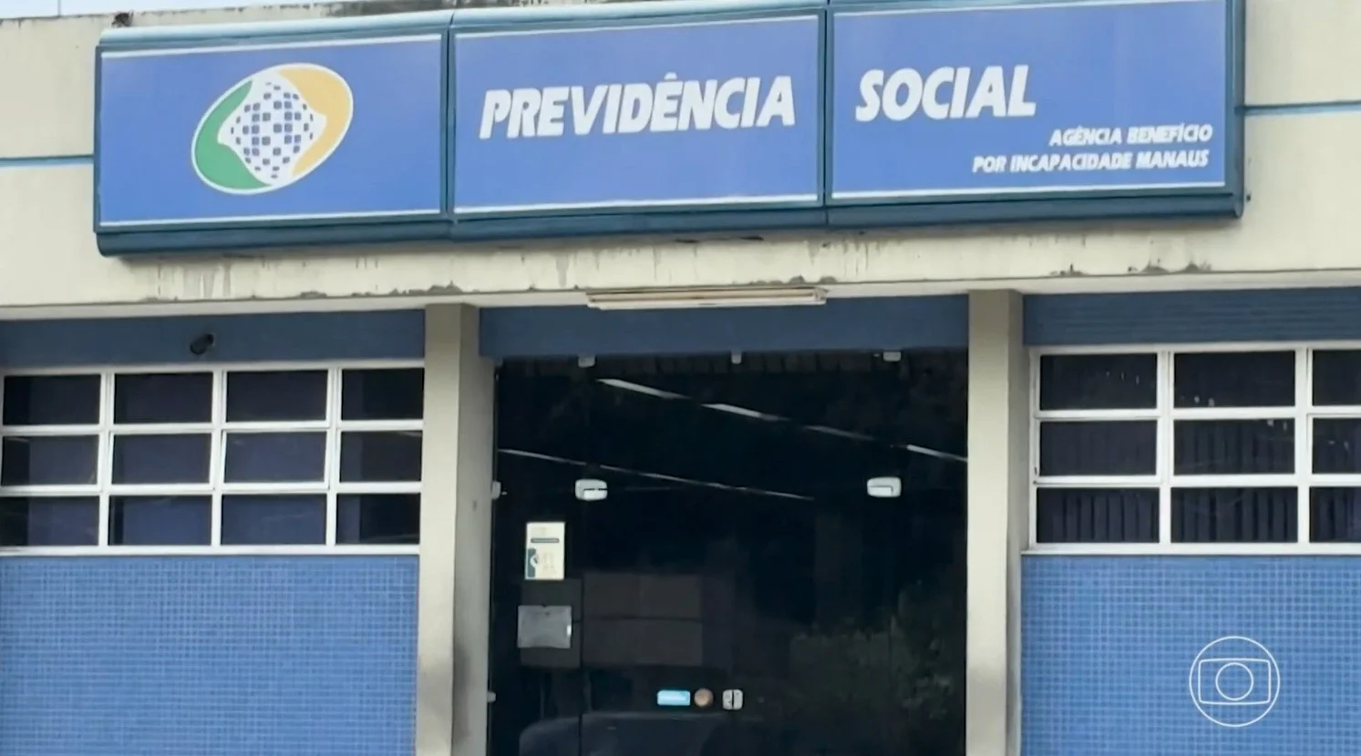 Servidor público brasileiro frustrado diante de um monitor de computador em um escritório governamental, luz azulada da tela, pilhas de pastas de processos ao fundo.