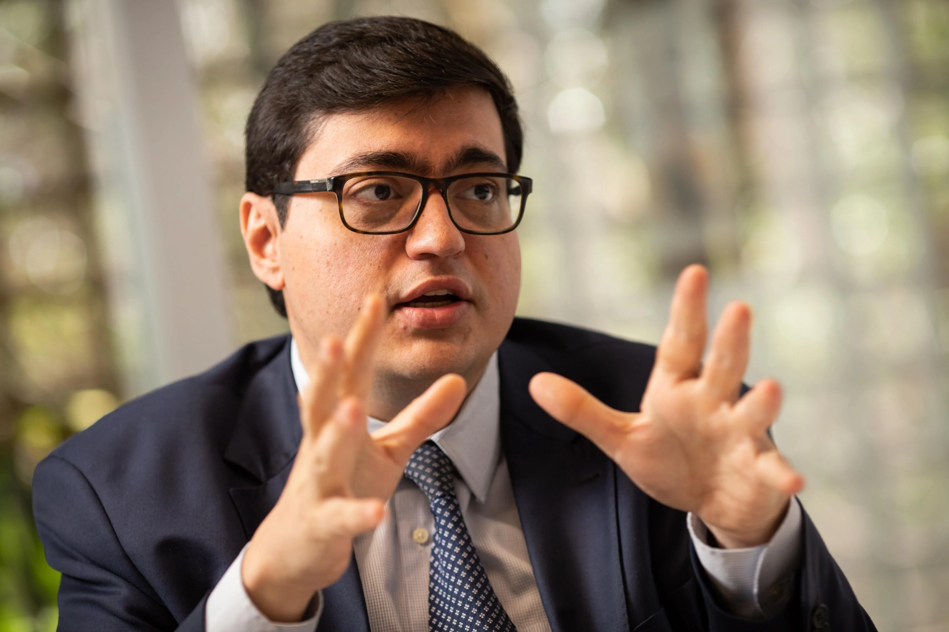 Mãos segurando moedas e cédulas de real sobre um mapa do Brasil, com uma bomba de combustível e gráficos financeiros ao fundo, simbolizando o impacto econômico da desoneração de combustíveis.