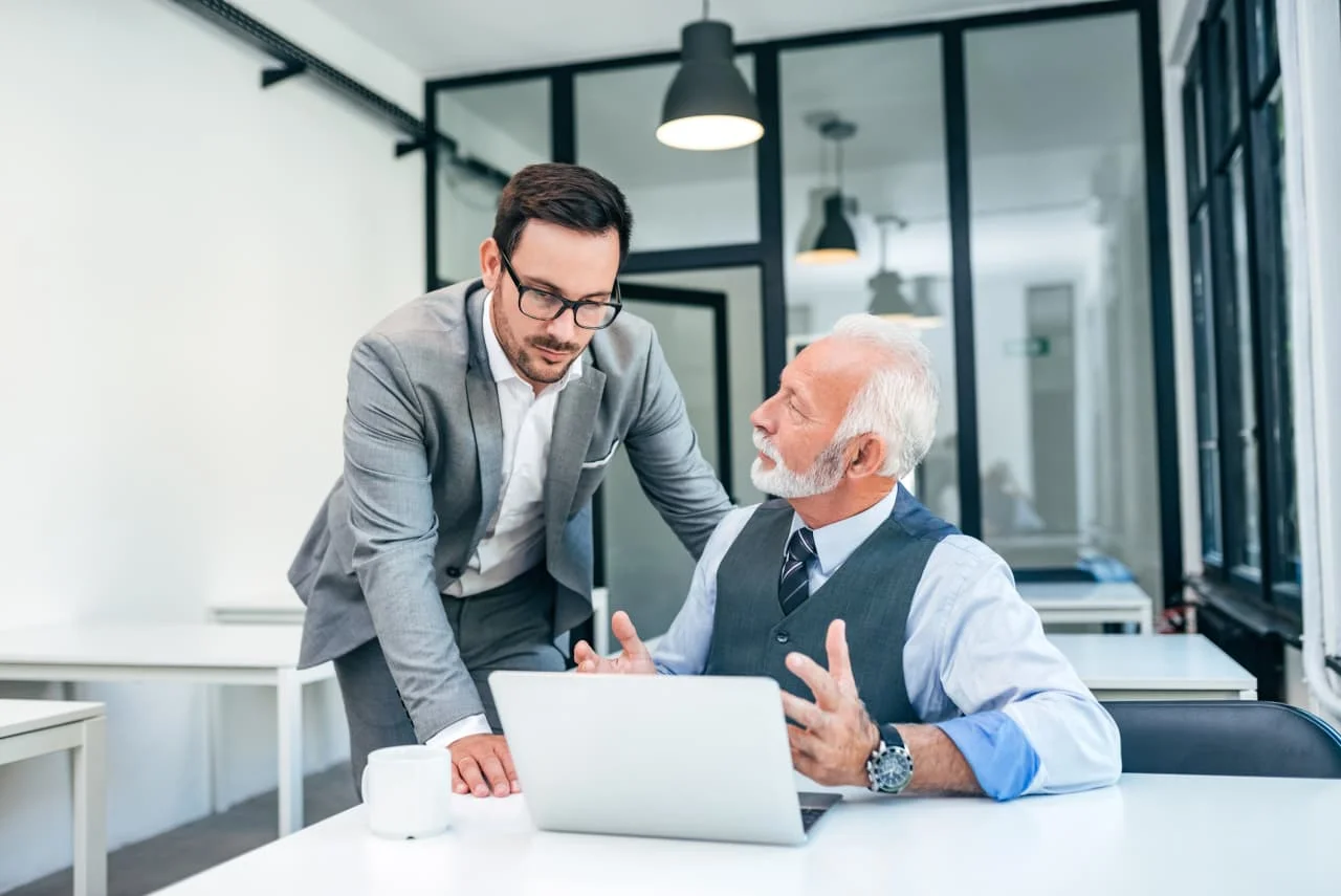 Mãos de diferentes gerações (jovens e idosos) interagindo sobre um gráfico financeiro em ascensão, simbolizando colaboração e valor da experiência, com dados e moedas ao fundo, em um ambiente corporativo moderno.