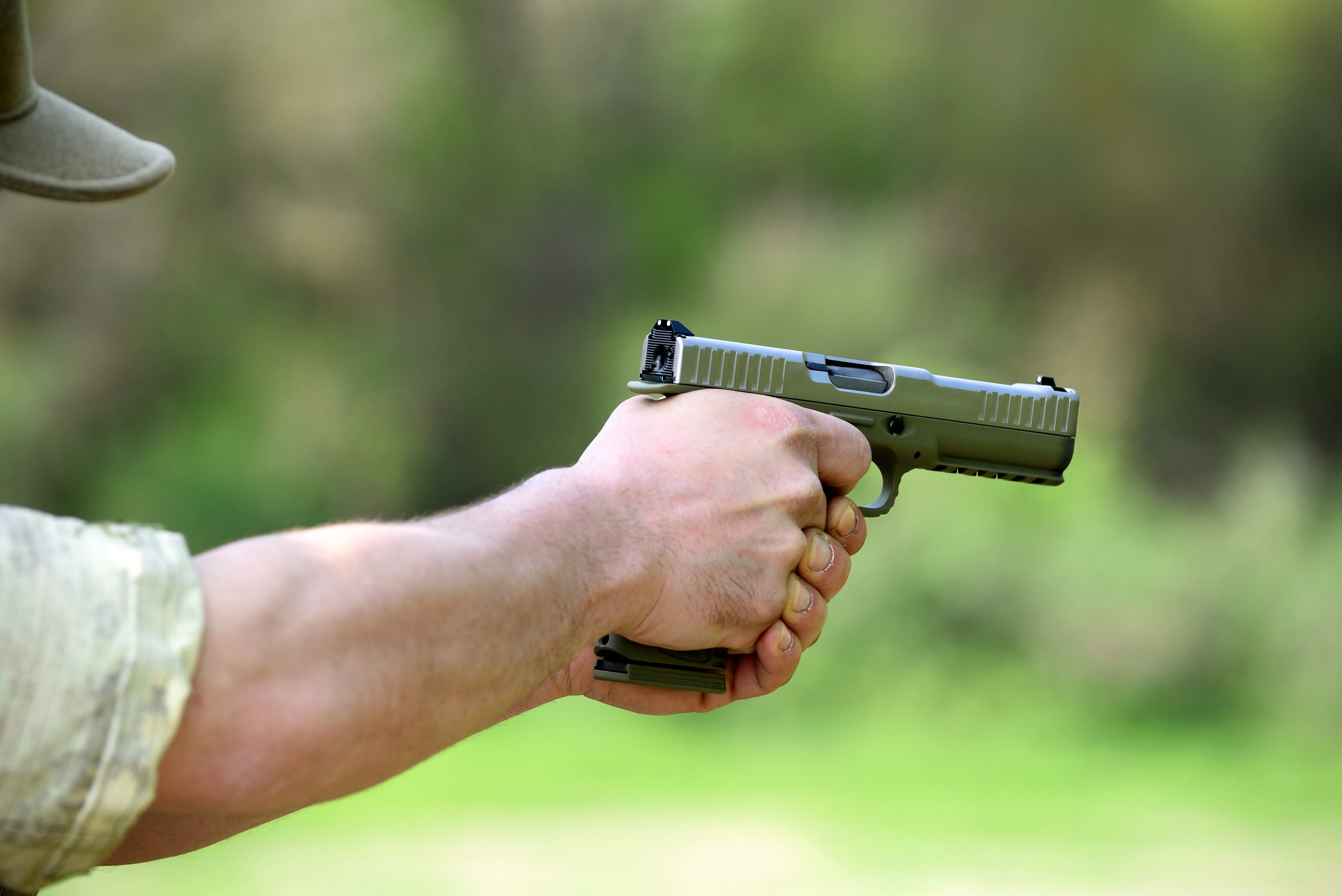 Moedas empilhadas e cédulas de dinheiro com uma arma de fogo e munições ao lado, simbolizando a proposta de uso do FGTS para compra de armamentos. Fundo desfocado com gráficos financeiros.