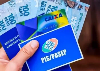 Trabalhador segurando smartphone com o aplicativo oficial do FGTS aberto, mostrando saldo e opções de saque, com moedas de Real ao fundo em ambiente iluminado.