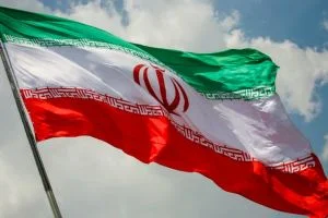 Delegados iranianos e americanos, representados por figuras em ternos, se reúnem em uma sala de negociações tensa, com mapas do Oriente Médio ao fundo. Há canetas e papéis na mesa.