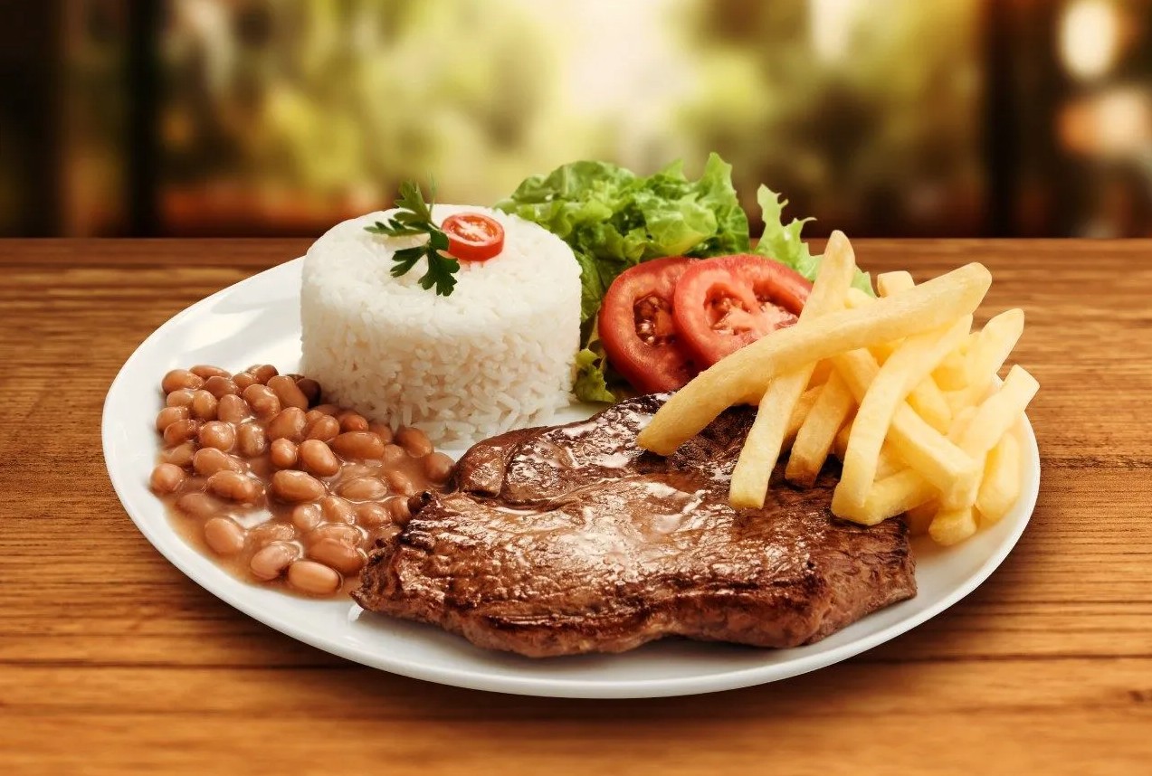 Uma refeição de prato feito tradicional brasileiro, vista de cima, com arroz, feijão, bife, batata frita e salada, em uma mesa de restaurante simples. A comida está apetitosa.