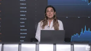 Mãos humanas segurando um tablet exibindo gráficos financeiros crescentes, com ícones de diferentes moedas e ativos ao fundo, simbolizando a diversificação de carteiras de ETFs da XP.